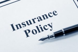 A pen on top of an insurance policy document. Insurance coverage if in an auto accident.