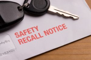 Car keys on top of safety recall notice mailer. Auto defect and automotive product liability.