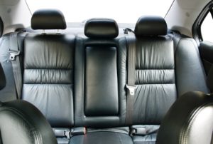 A vehicle's back seat with black leather seats. Defective Seats.