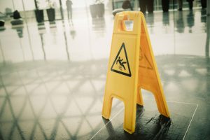 A yellow slip and fall warning hazard sign on floor. Premises liability.