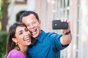 A couple taking a selfie photo. Taking selfies is extremely dangerous for the person taking the picture, anyone in the car, and for everyone else on the road.