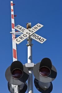 A railroad crossing sign and red and white arm. Remember to Stop, Look, and Listen at railroad crossings to prevent and accident with a train.