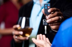 Person holding a wine glass hands over their car keys to a designated driver. December is National Impaired Driving Prevention Month.