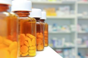 a row of prescrion medication pill bottles in a pharmacy. Risperdal dangerous drug side effects.
