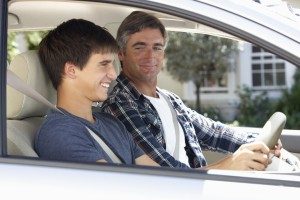 Teen driving with his dad. The number of teens obtaining drivers licenses is on a decline. 
