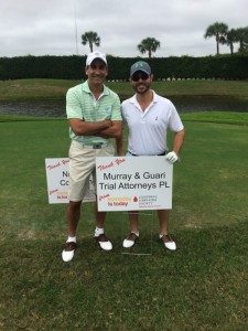 Attorney Jason Guari and Scott Perry at the Leukemia and Lymphoma Society's Golf Tournament. Attorney's pictured on green in front of Murray Guari sponorship sign.