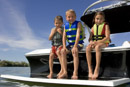 Kids with life preservers on sitting on back of a boat. Learn about the top 10 contributors to boating accidents.