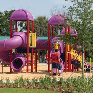 Purple, yellow and red plastic public playground. Unsafe playgrounds – how to prevent closed head injuries and other playground accidents.