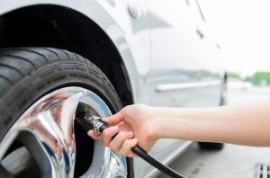 A woman's hand pumping air into a tire for increasing pressure.