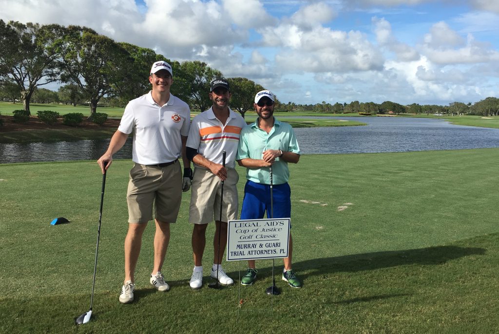 Attorneys Keith Hedrick, Jason Guari and Scott Perry on the golf course by their Hole Sponsor Sign.