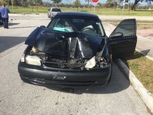 Crashed black automobile with crushed in hood
