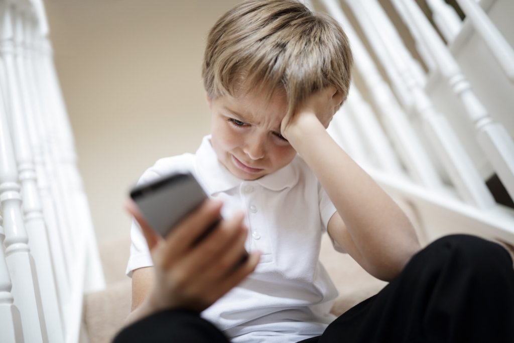 Child looking at cell phone crying