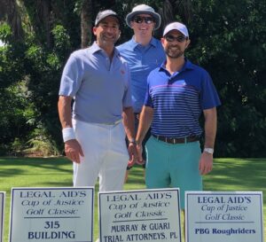 Jason Guari, Scott Perry & Keith Hedrick by Sponsorship Sign for Cup of Justice Golf Tournament
