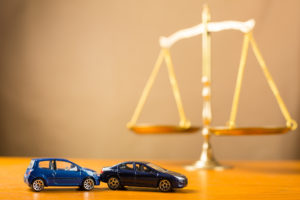 Gold Scales of Justice with two matchbox cars in rear-end situation