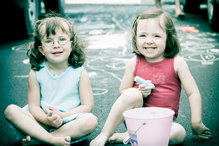 Two Little Girls Sitting in Driveway with Chalk