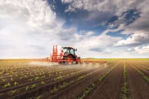 Tractor spraying herbicides on agricultural land
