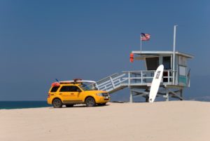Life guard station at the ocean with yellow truck and surf boards