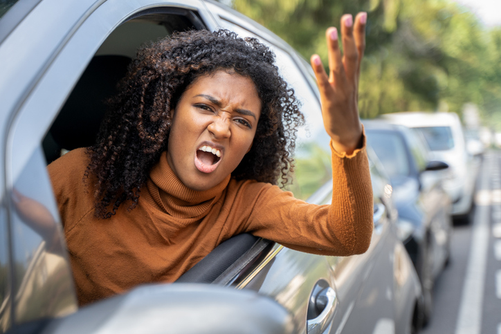 Aggressive woman driving car shouting at someone