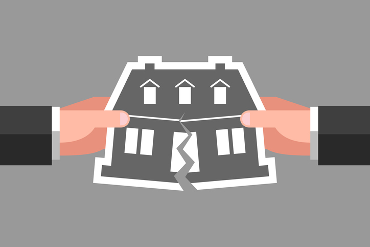 Two hands are tearing icon of house over gray background. Concept of division of property, real estate, inheritance partition