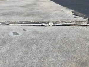 a picture of a roadway where the crosswalk is damaged due to lack of maintenance showing danger 