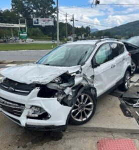 A white Ford Escape with heavy damages to the front and drivers side of the vehicle
