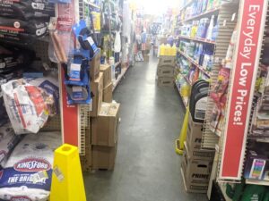 A store filled with various boxes and bags of supplies in middle of the aisle impacting walking and increasing trip and fall hazard.