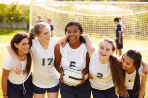 Members Of Female High School Soccer Team Smiling To camera