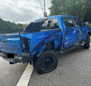 Blue pickup truck with major passenger side damage due to a motor vehicle accident.